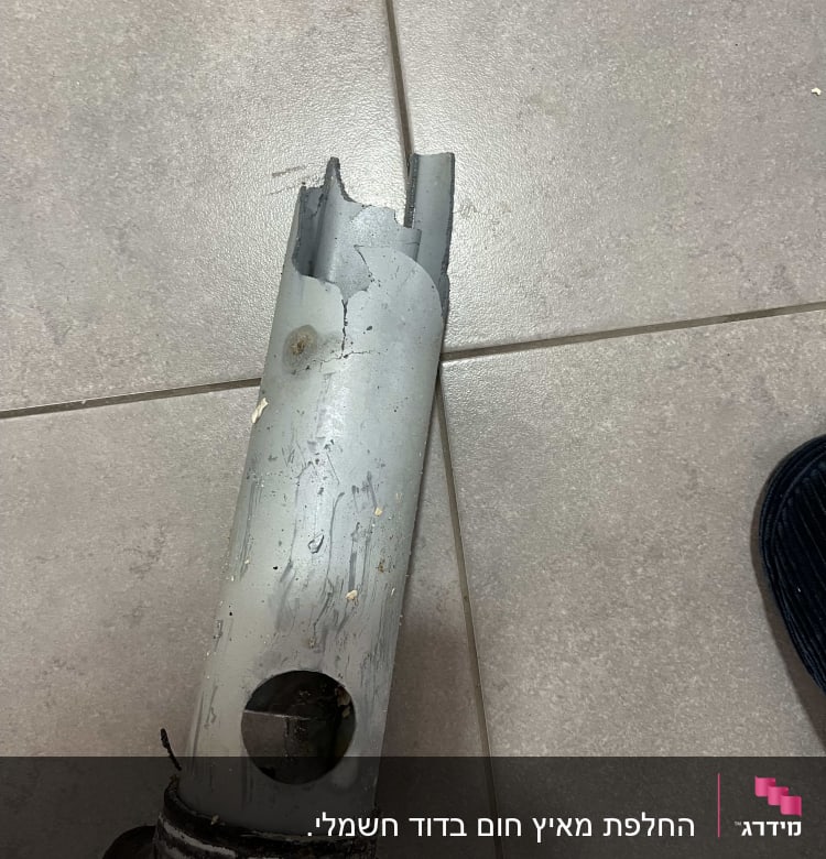 צינור שבור עם חור על רצפה אפורה